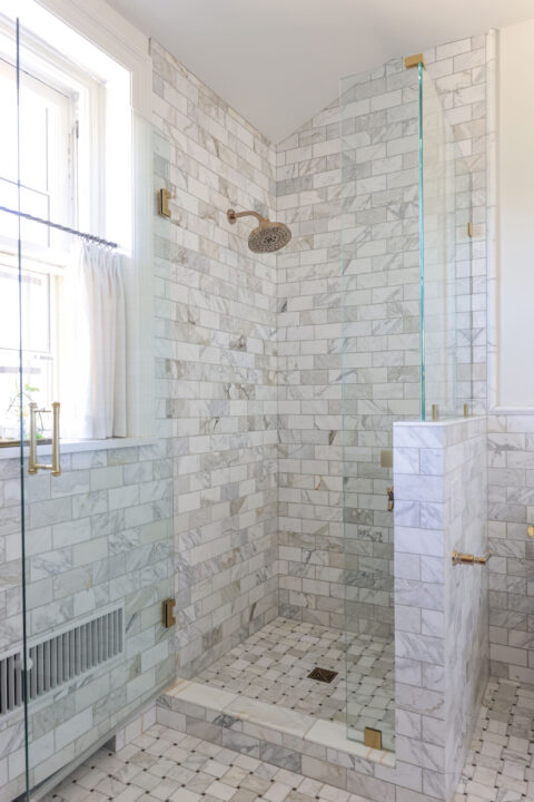 A modern Tulsa bathroom remodel featuring a glass door walk-in shower with a curb, subway tile, and a pony wall.