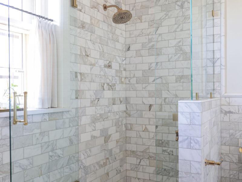 A modern Tulsa bathroom remodel featuring a glass door walk-in shower with a curb, subway tile, and a pony wall.