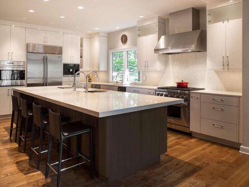 Tulsa kitchen design and remodel featuring a large island with seating, cabinet storage, a quartz countertop, a Galley sink workstation, and white perimeter cabinets with stainless steel Sub-Zero, Wolf, and Miele appliances, including a coffee maker.