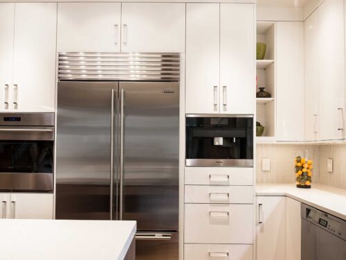 Tulsa kitchen remodel featuring tall storage with stainless steel Sub-Zero refrigeration, a Wolf oven, a Miele coffee system, and white flat-panel cabinet and drawer storage.