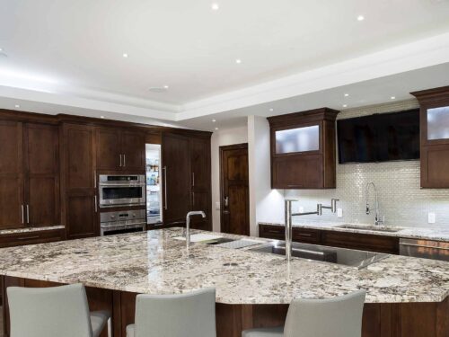 Large kitchen island seating granite counter, brown cabinet storage, undermount clean-up sink, Galley Workstation, Thermador, GE Monogram appliances, frosted glass cabinets Tulsa kitchen remodel