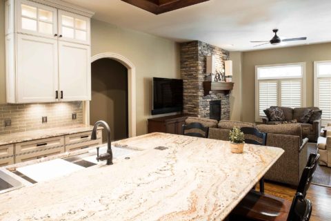 Marble counter kitchen island, Galley Workstation, cream painted cabinet storage, subway tile backsplash, adjoining living room Tulsa kitchen remodel