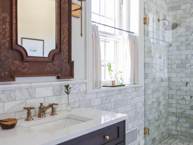 A classic and stylish Tulsa bathroom design and remodel featuring a single-sink vanity, wainscoting with a subway tile backsplash, and a modern glass door shower.