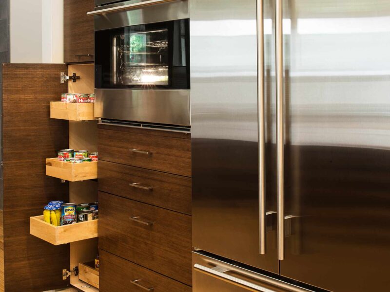 Tulsa kitchen remodel featuring a tall pantry pullout storage unit, a Sub-Zero French door refrigerator and freezer, a Wolf oven, and bamboo cabinets.
