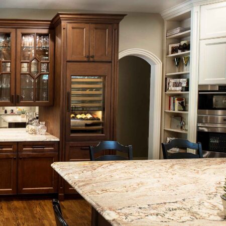 Tulsa kitchen beverage space, mirror backsplash, Sub-Zero tall wine refrigerator, brown cream cabinet storage, Wolf wall ovens, tall open shelf storage Tulsa kitchen design remodel