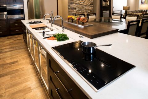 Galley kitchen island storage, Wolf gas and induction cooktops, large island cabinet storage, quartz counter, pop-up television, vinyl wood flooring Tulsa kitchen remodel