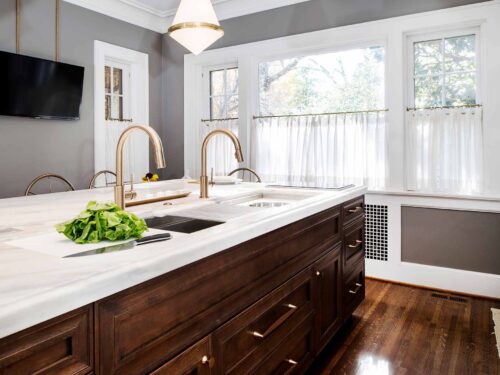 Tulsa kitchen remodel featuring a kitchen island with a Galley Workstation, red birch cabinet storage, white marble countertops, and a Wolf induction cooktop.
