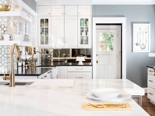 Tulsa kitchen remodel featuring a marble countertop, mirror backsplash, an adjoining bar space, a Galley Workstation, and an apron-front sink.
