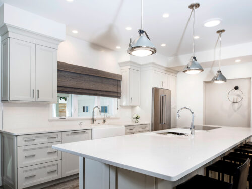 Tulsa kitchen remodel featuring an island with a Galley Workstation and seating, an apron-front clean-up sink, white cabinets with crown molding, and wood flooring.