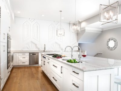 Art deco white Tulsa penthouse kitchen remodel with Galley Workstation and transitional gas cooktop on the large island including base storage and wood flooring