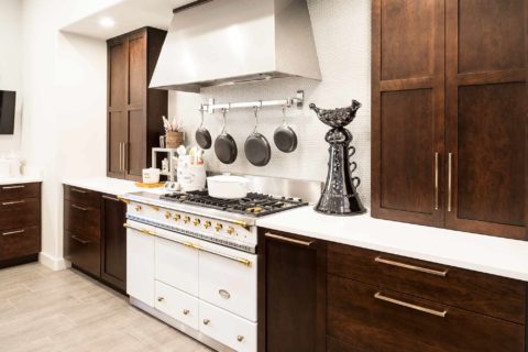 Lacanche french gas range in Tulsa kitchen remodel with vent hood rich brown cabinet storage, ceramic tile backsplash and quartz counter-top
