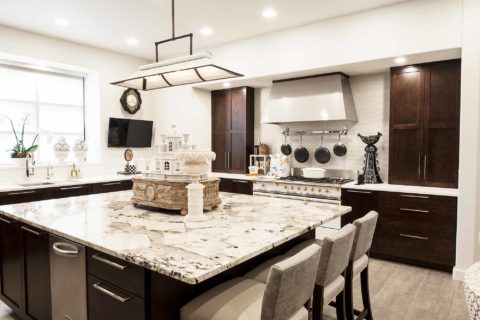 Classy Tulsa kitchen remodel with marble counter-tops, island seating, rich brown base cabinet storage, decorative pendant lighting and Lacanche french range