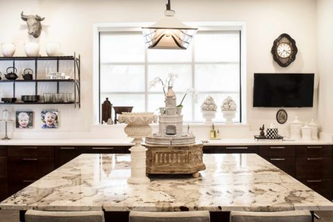 Classy Tulsa kitchen remodel with marble counter-tops, island seating, rich brown base cabinet storage, decorative pendant lighting and open shelves
