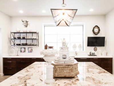 Classy Tulsa kitchen remodel with marble counter-tops, rich brown base cabinet storage, island with decorative pendant lighting and open shelves