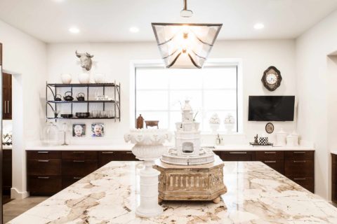Classy Tulsa kitchen remodel with marble counter-tops, rich brown base cabinet storage, island with decorative pendant lighting and open shelves