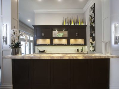 Contemporary designed and remodeled Tulsa open bar area, lit frosted glass wall cabinets, dark brown cabinet storage, glass tile backsplash and granite counters
