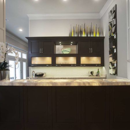 Contemporary designed and remodeled Tulsa open bar area, lit frosted glass wall cabinets, dark brown cabinet storage, glass tile backsplash and granite counters