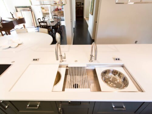 Tulsa kitchen remodel featuring an island with a Galley Workstation kitchen sink, seating, quartz counters, Mockett pop-ups, and an open living room space.
