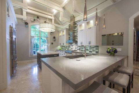 Tulsa kitchen remodel featuring an island peninsula with seating, a Galley Workstation kitchen sink, a professional gas rangetop, a vent hood, and pendant lights.