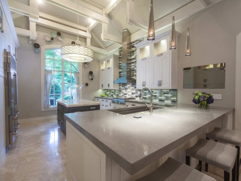 Tulsa kitchen remodel featuring an island peninsula with seating, a Galley Workstation kitchen sink, a professional gas rangetop, a vent hood, and pendant lights.