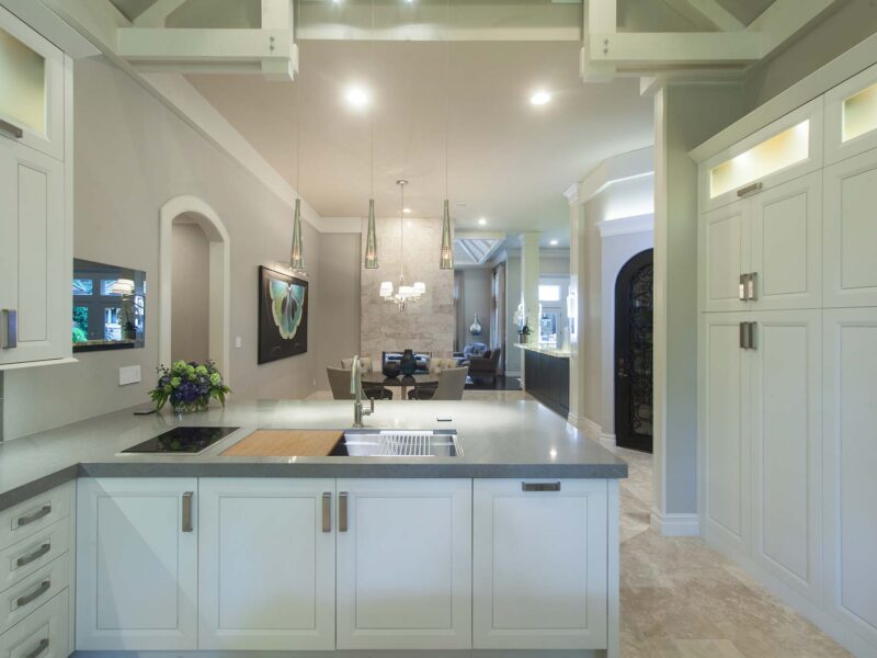 Tulsa kitchen remodel featuring a kitchen peninsula with white cabinets, a Galley Workstation, tall cabinet storage, and decorative pendant lights.