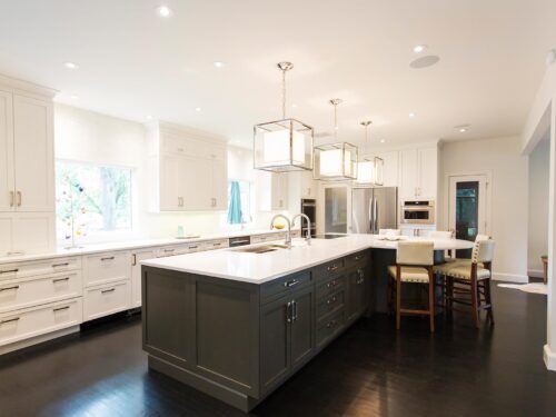Tulsa kitchen remodel featuring a large kitchen island with white stained cabinets, quartz counters, vinyl floors, decorative pendant lights, a Galley Workstation, and an induction cooktop.