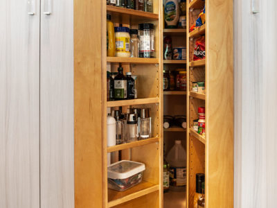 Large open transitional white Tulsa kitchen remodel with tall pantry storage with clear cabinet hardware for storing condiments and dry food goods and wood flooring