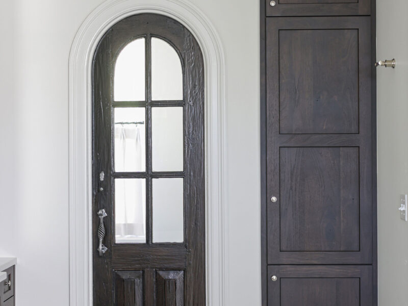A beautiful Tulsa master bathroom remodel featuring tall storage cabinets, crown molding, a decorative ceiling, and an arched entry door.