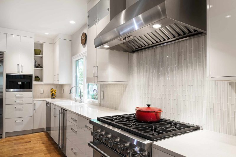 Modern and functional Tulsa kitchen remodel with Wolf gas range cooking and ventilation, white cabinets, ceramic tile backsplash, Miele coffee and base cabinet storage