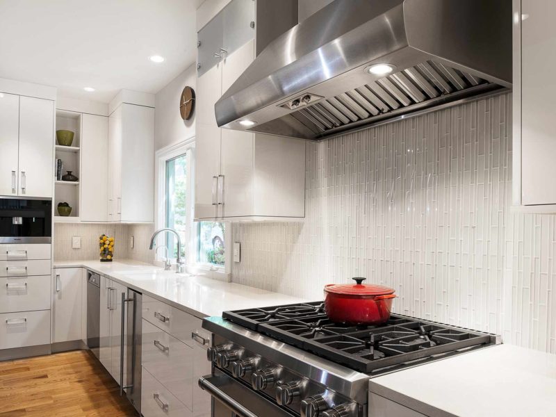Modern and functional Tulsa kitchen remodel with Wolf gas range cooking and ventilation, white cabinets, ceramic tile backsplash, Miele coffee and base cabinet storage