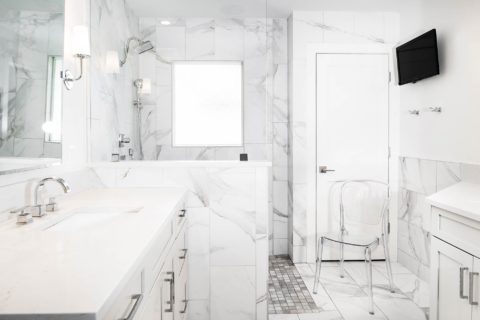 Modern Tulsa bathroom with vanity base cabinet drawer storage, walk-in shower, large tile walls and wall mounted television
