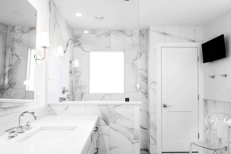 Modern fresh white Tulsa master bathroom with vanity walk-in shower, glass partition, tile walls and wall mounted television