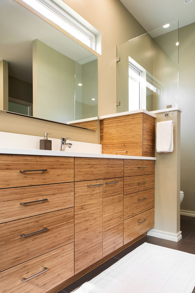 Tulsa bathroom design and remodel with quartz counter and backsplash, brown wood grain cabinet storage, modern vanity mirror and slate gray tile flooring