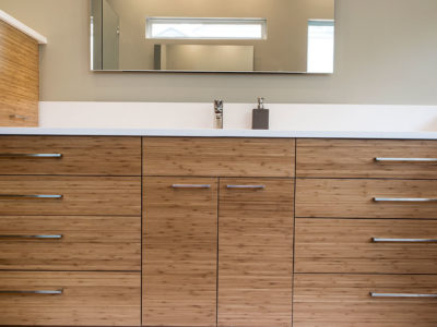 Modern Tulsa bathroom design and remodel with quartz counter and backsplash, medium brown wood grain cabinet storage, modern vanity mirror and slate gray tile flooring