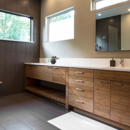 Modern Tulsa bathroom with quartz counter with backsplash, brown wood grain base cabinet storage and modern vanity mirror
