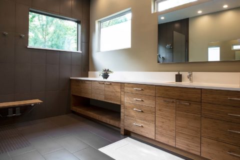 Modern Tulsa bathroom with quartz counter with backsplash, brown wood grain base cabinet storage and modern vanity mirror