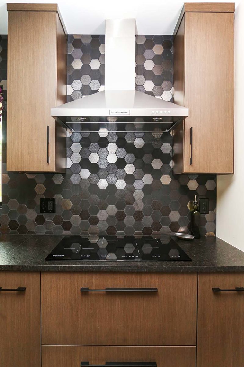 Tulsa kitchen design and remodel with flat door style base and wall cabinet storage and stainless canopy vent hood with decorative tile backsplash and induction cook top