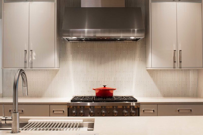 Tulsa kitchen design and remodel with stainless Wolf professional gas range and vent hood cooking space, ceramic tile backsplash and white cabinetry
