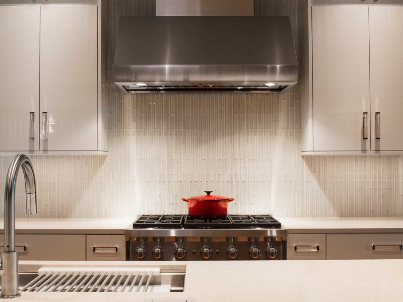 Tulsa kitchen design and remodel with stainless Wolf professional gas range and vent hood cooking space, ceramic tile backsplash and white cabinetry
