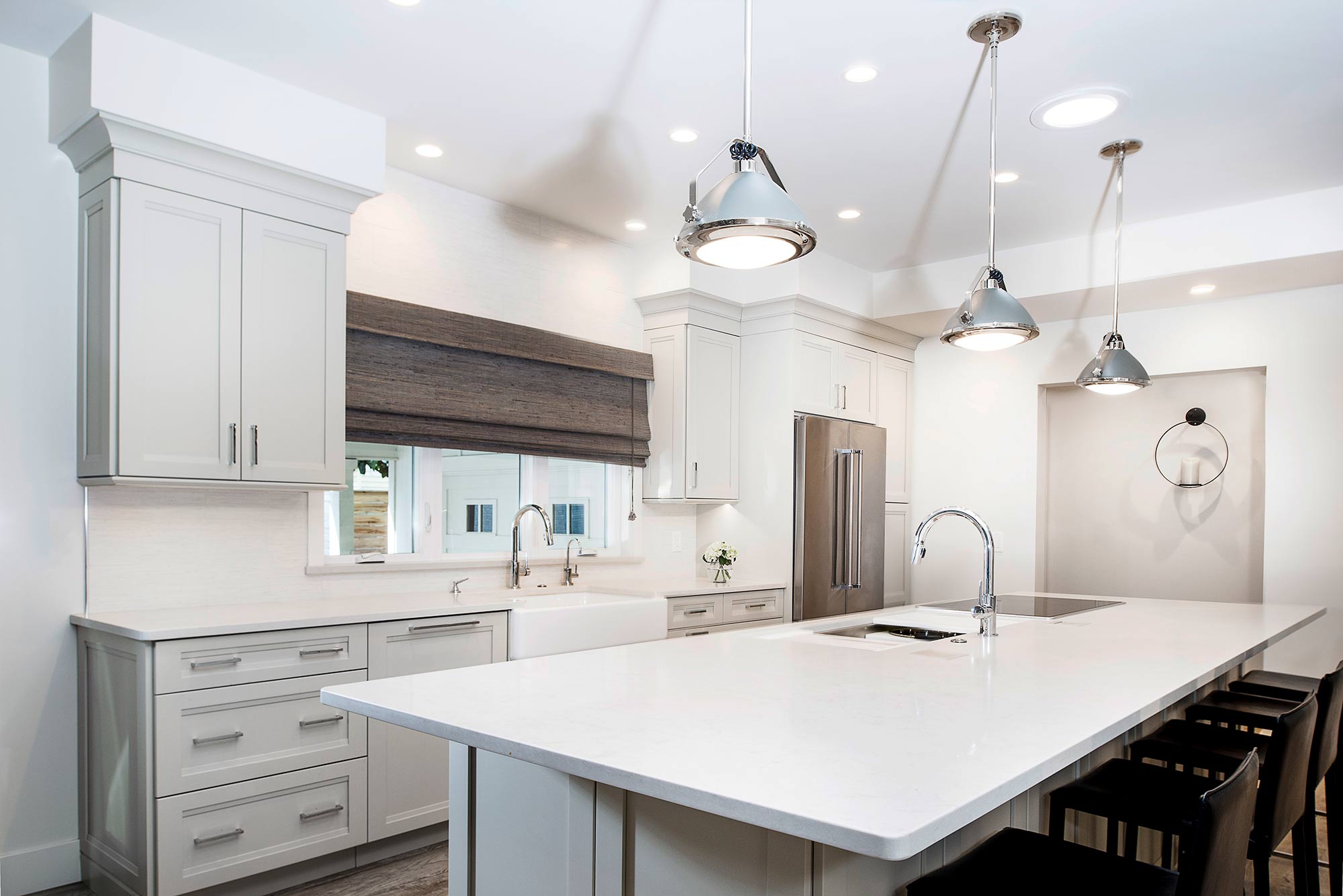 Modern white Tulsa kitchen remodel with large island, quartz countertops, Galley Workstation, farmhouse sink, stainless appliances, vinyl flooring and island pendants