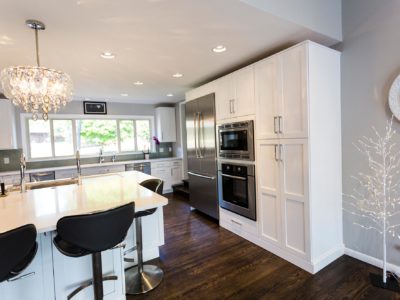 Open and functional Tulsa kitchen design and remodel with white tall cabinet storage, stainless Bosch refrigeration and cooking appliances and wood flooring