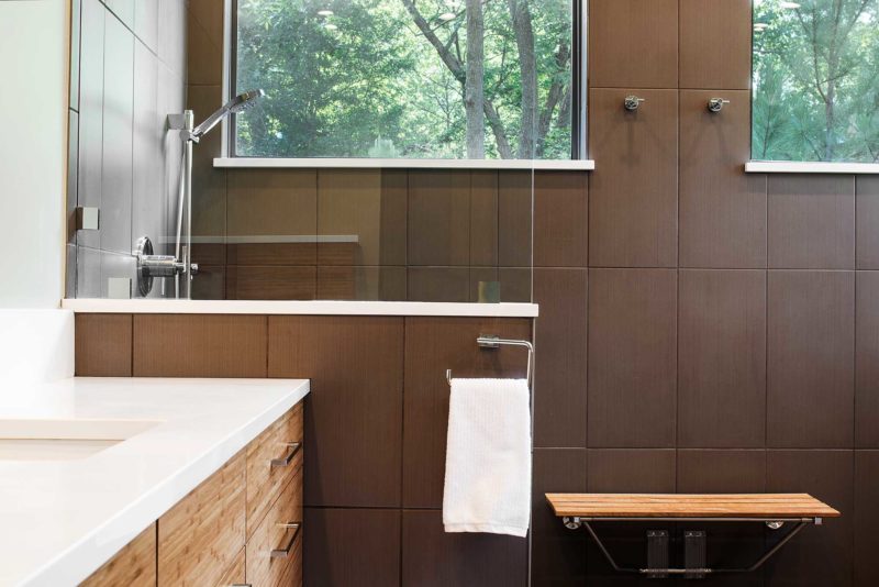 Open contemporary Tulsa master bath design and remodel with walk-in shower, wood bench seating, medium brown wood grain base vanity storage, quartz counter-tops and glass partition