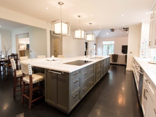Tulsa kitchen remodel featuring an open kitchen, a large island with a Galley Workstation, stained white cabinet storage, quartz counters, vinyl floors, decorative pendant lights, and an induction cooktop.