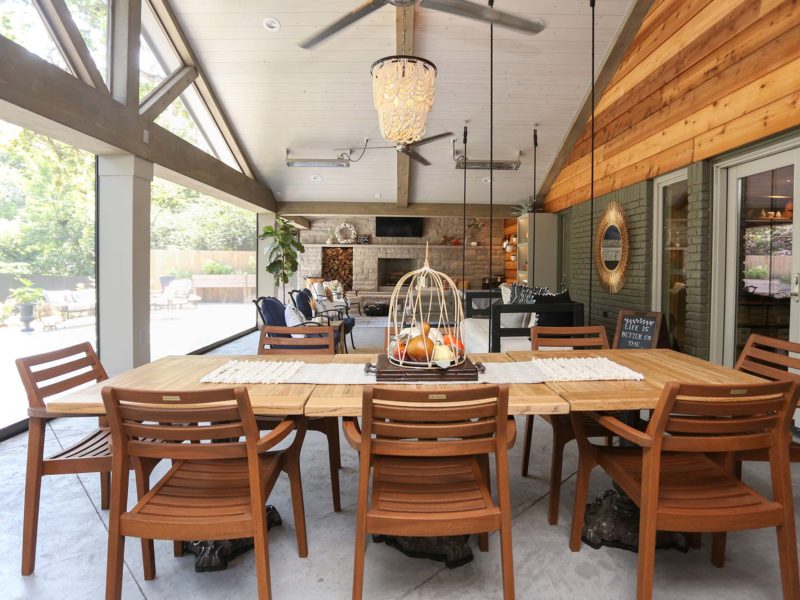 Spacious open-concept patio featuring outdoor dining table and natural stone fireplace in Tulsa patio design and remodel.