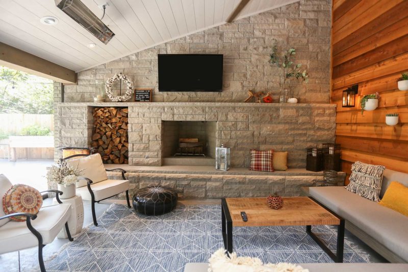 Spacious open Tulsa patio design and remodel living space with stone wood burning fireplace, concrete flooring and vaulted ceiling with wood paneling.