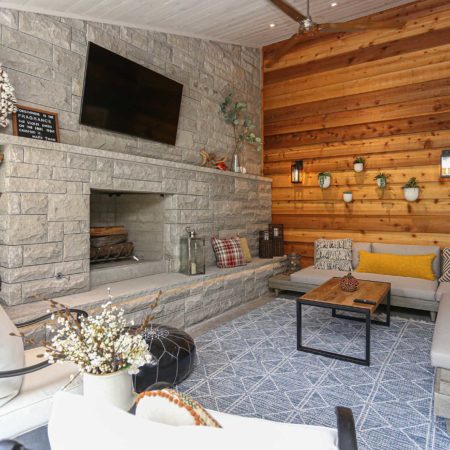 Beautiful Tulsa patio design and remodel with stone wood burning fireplace, wall mounted television, wood paneling, concrete flooring and outdoor furniture