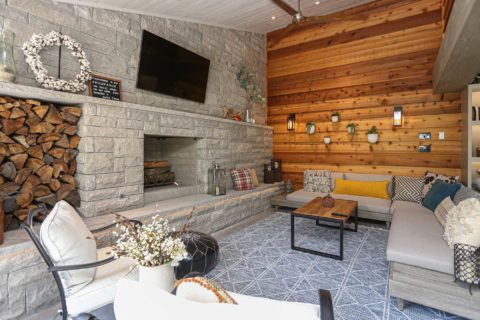 Beautiful Tulsa patio design and remodel with stone wood burning fireplace, wall mounted television, wood paneling, concrete flooring and outdoor furniture