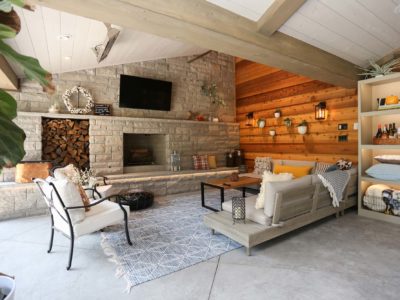 Spacious open Tulsa patio design and remodel living space with stone wood burning fireplace, concrete flooring and vaulted ceiling with wood paneling