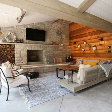 Spacious open Tulsa patio design and remodel living space with stone wood burning fireplace, concrete flooring and vaulted ceiling with wood paneling