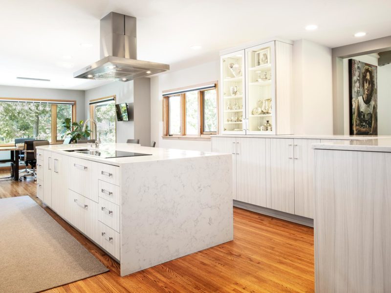 Open transitional white Tulsa kitchen design and remodel, Bosch stainless professional vent hood, island with waterfall edge counter, Bosch induction cooktop, Galley Workstation and wood floors